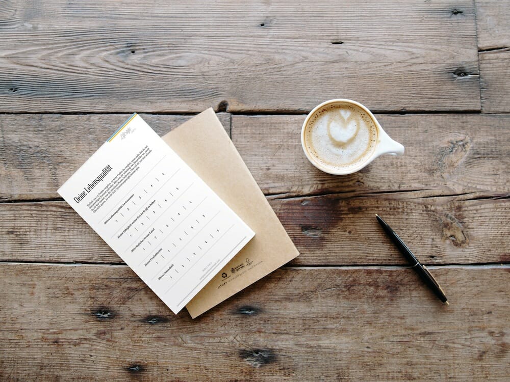Notepad on a wooden table with a cup of coffee CleanShot 2022 07 29 at